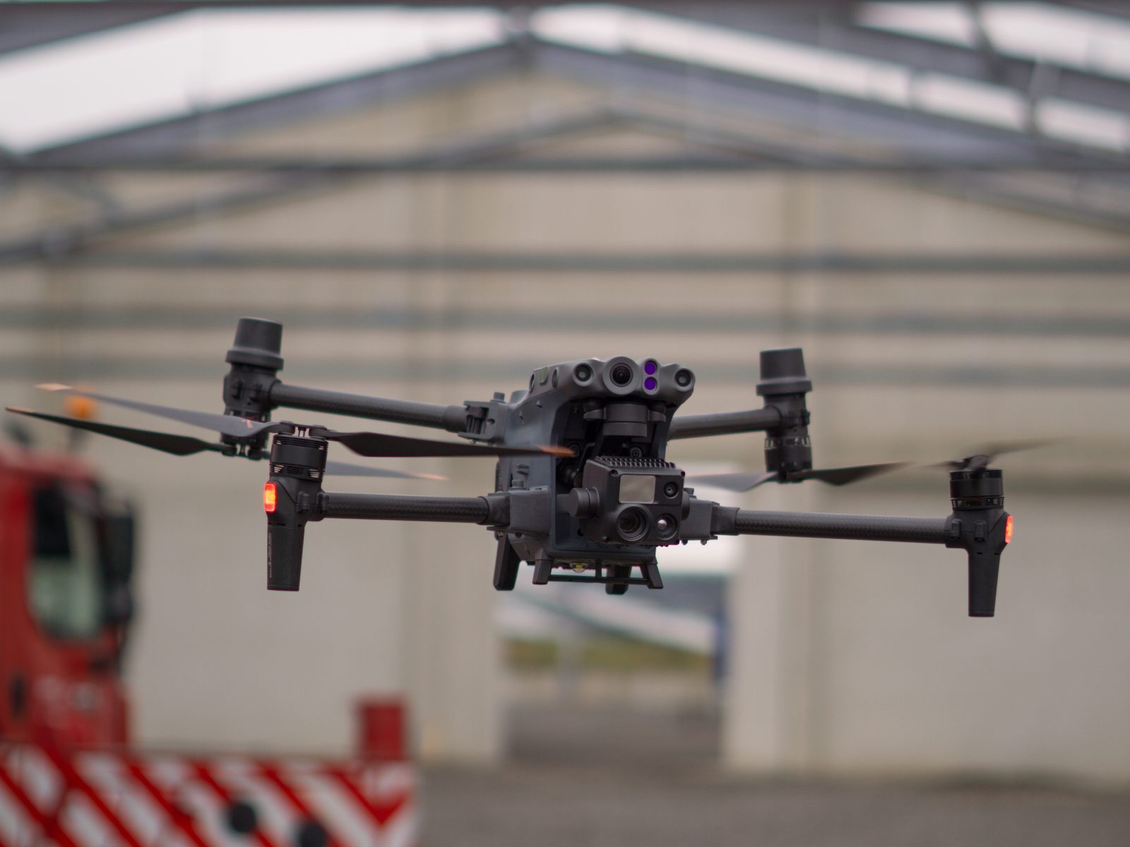 Eigene Inspektionsdrohne im Schwebeflug vor einer Industriehalle, Sensorkopf mit Kameramodulen erkennbar
