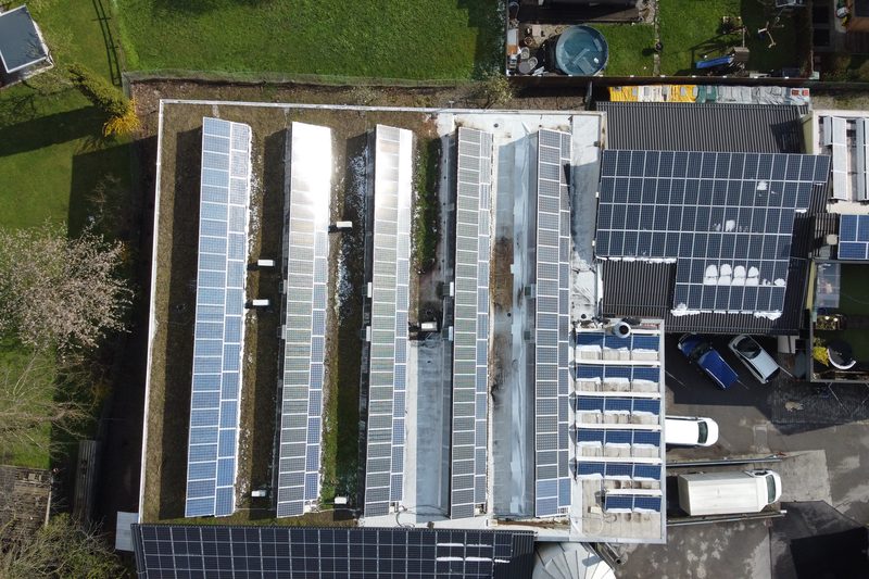 Senkrechtes Luftbild eines Industrieflachdachs, vollständig mit Photovoltaikmodulen belegt